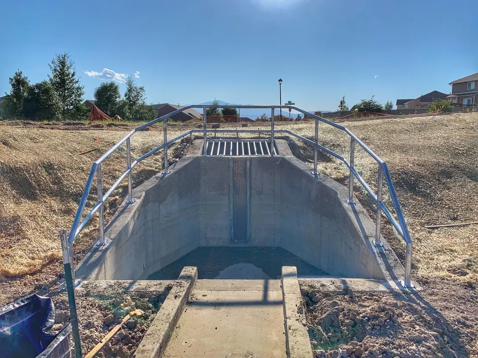 Steel safety railing installed around a concrete drainage headwall