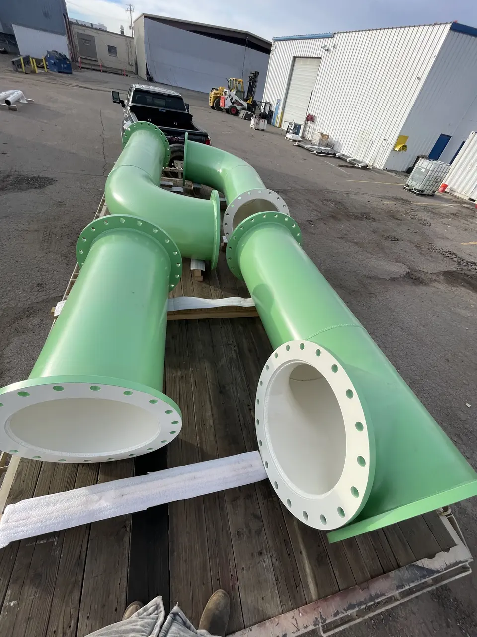 Green painted flanged pipe spools with lined interiors staged on a trailer