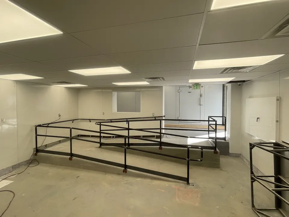 Black steel guardrail around a raised platform and ramp in a commercial interior