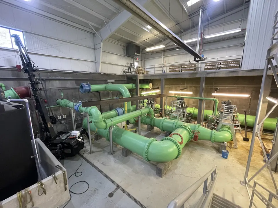 Green painted pump station piping with steel supports and walkways