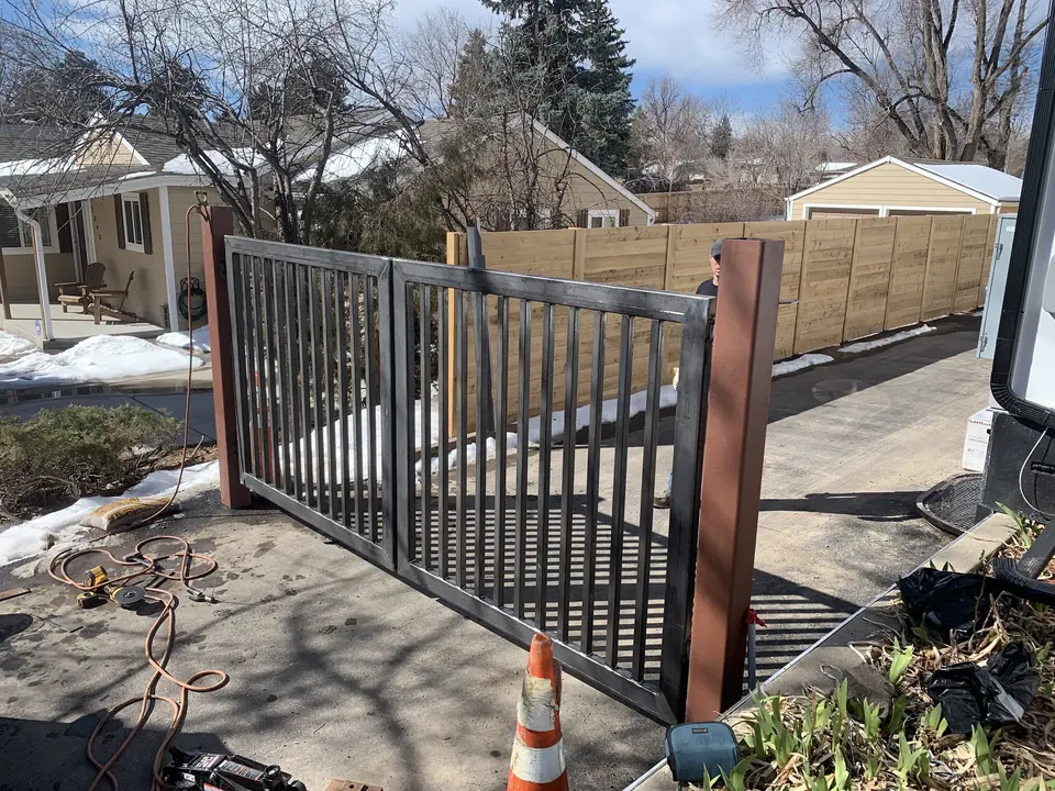 Black steel picket driveway gate installed between masonry posts