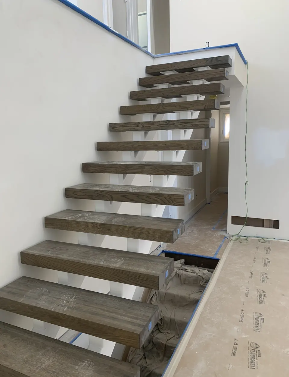Interior steel stair with cantilevered wood treads against a white wall